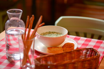 Okroshka. Summer light cold yogurt soup with cucumber, radish, eggs and dill in a bowl. Dinner in restaurant.
