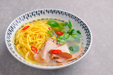 Japanese ramen soup with noodles, beef, egg, fresh parsley and sweet pepper on gray background. Copy space banner.