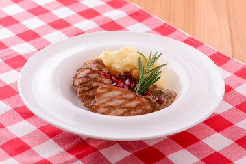 Grilled steak seasoned with salt and herbs. Served with mashed potatoes and pomegranate seeds.