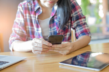 Young women using phone on work desk on table at cafe,selective focus.