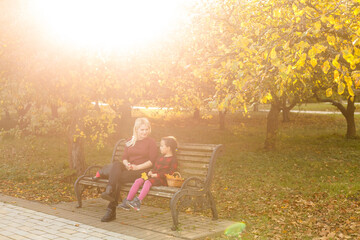 mother and daughter on a bench in autumn park
