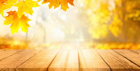 Naklejka na ściany i meble Beautiful autumn background with orange gold maple leaves on background of sunlight with soft blurred bokeh and empty wooden table planks.