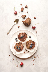 Homemade fresh chocolate muffins with berries and chocolate pieces. Top view.