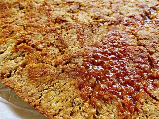 Closeup view of a rustic and traditional homemade flapjack. Ingredients are golden syrup, unsalted butter and rolled porridge oats. Gooey and sticky home baked dessert.