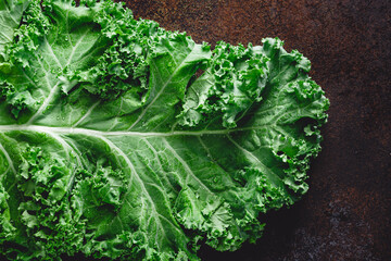 Fresh curly kale salad over dark rustic background. Top view, healthy eating background. - obrazy, fototapety, plakaty
