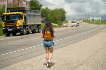 Tourists with backpacks hitchhiking on road. Hitchhiking tourism concept. Travel hitchhiker girl walking on road