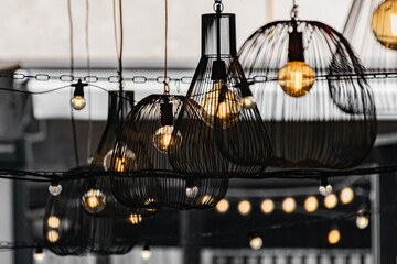 Cafe on the sidewalk in the open air decorated with yellow bulbs. Antique light decoration in a modern interior.