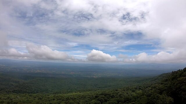 The Video moves from right to the left side of clouds move on the sky in the daytime bright and tree sway in the wind on the mountain at Phu Hin Rong Kla , Phetchabun , Thailamd.