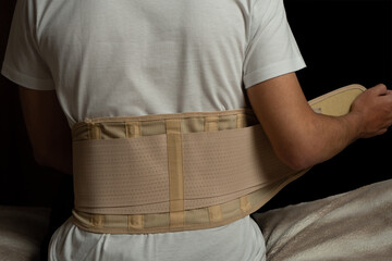 Man sitting at a bed and has pain in the back. Spine support for muscle back