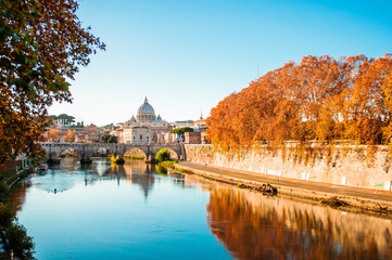 Autumn time in Rome. Beautiful river view. Vatican dome of Saint Peter Basilica Cathedral over Tiber river. Travel in Italy. Golden trees.