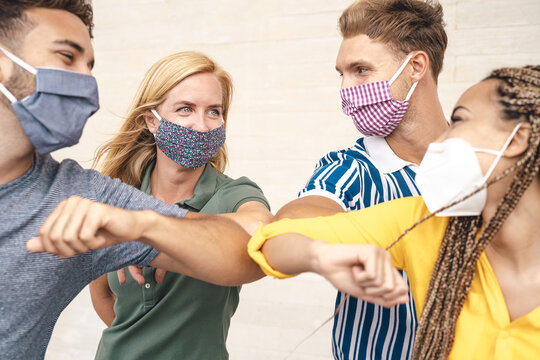 Young friends wearing face mask doing new social distancing greet with elbows bumps for preventing corona virus spread - Physical distance and friendship safety greetings concept