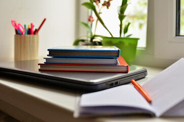 Home schooling. Distance learning for students. Books and laptop near the window.