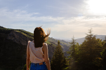 Naklejka premium Nice woman looking at a mountain sunset while on vacation. Selective focus