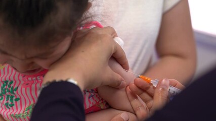 Doctor vaccinates the baby sitting in the arms of the mother. Crying baby, medical manipulations, pediatrics concept. Immunization program.