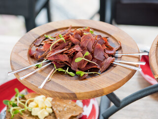 Sliced ​​jerky on a wooden plate. Selective focus.