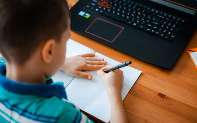 Distance learning online education. A schoolboy boy studies at home and does school homework. A home distance learning