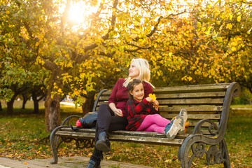 Happy mother and daughter embracing on a bench in an autumn park