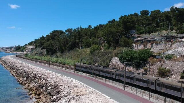 Following a train from above in two track railway on coastline in Lisbon, Portugal