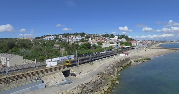 Departing train in station and follow from side in two track railway on coastline in Lisbon, Portugal