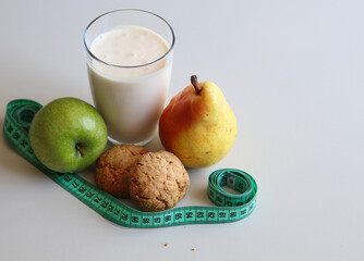 a glass of kefir, oatmeal cookies, ripe apple and pear on a white background close up