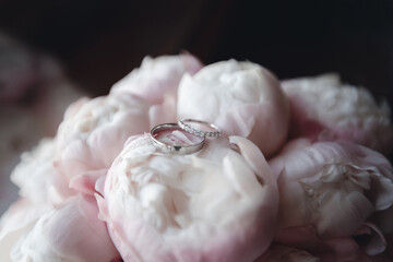 Fototapeta na wymiar wedding rings on peonies flowers macro close up. jewellery and gems