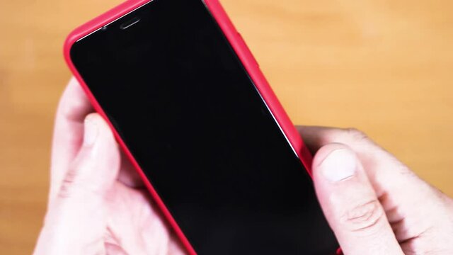 male hold twists in hands a smartphone in a red case