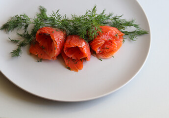 salmon slices and dill on a white plate on a white background close up