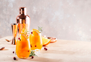 Orange cocktail with cranberry, rosemary and ice. Alcoholic, non-alcoholic drink beverage, copper...
