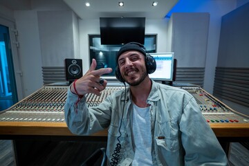 A happy professional male sound producer is smiling satisfied in camera while recording a new song...