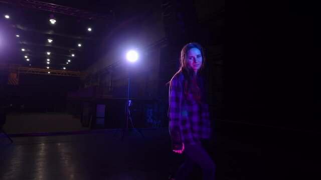 Circular view of beautiful smiling young woman roller-skating in circle, swirling on stage under bright blue neon pink spotlight looking at camera hypnotic look. Free leisure time in sport concept
