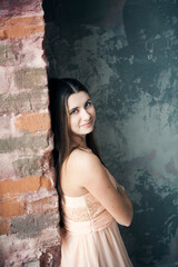 Fototapeta premium Young beautiful woman in evening dress posing and dancing in loft studio.