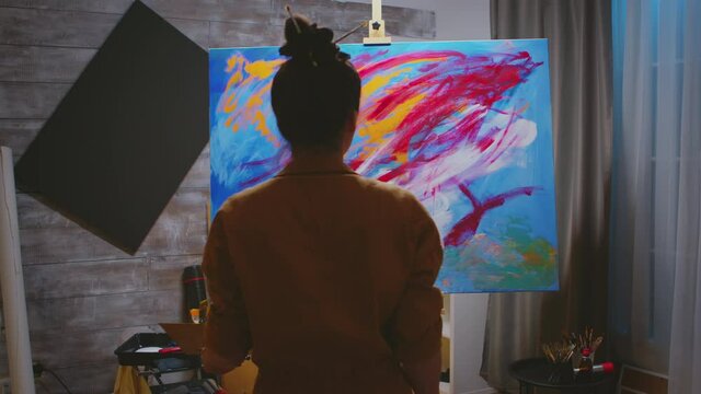 Young woman using her imagination while painting on canvas. Modern artwork paint on canvas, creative, contemporary and successful fine art artist drawing masterpiece
