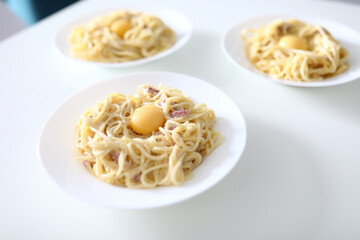 Close-up of tasty pasta with bacon egg and sauce. Bolognese served on white plate for company of people. Yummy breakfast. Traditional italian food and healthy eating concept