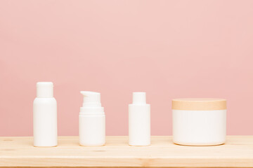 White cosmetic products on a pink background and wooden base. Natural cosmetics for branding mockup concept. Copy space.Healthy liftstyle concept