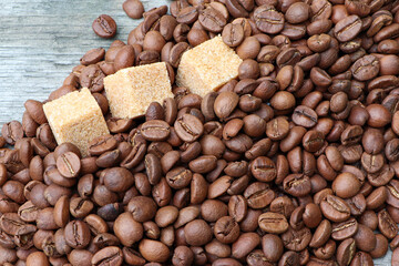 Roasted coffee beans and cane sugar on a grey wooden background. Flat lay