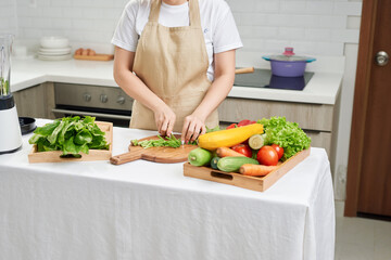 woman hand cutting salad on chopping wood board with sharp knife and cooking vegetables salad in kitchen