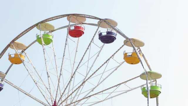 A Rainbow colored Ferris wheel spins around and around during a summertime music festival. The people are prepared to enjoy the ride in Chicago.