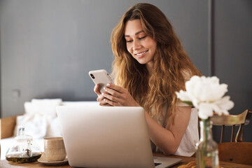 Beautiful young smiling girl sitting at the kitchen table