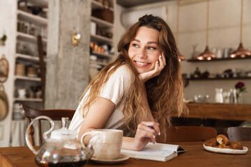Beautiful young smiling girl sitting at the kitchen table