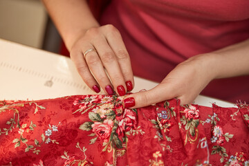 tailor woman sews red dress. Tailor working in her tailor shop