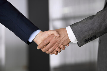 Business people in office suits standing and shaking hands, close-up. Business communication concept. Handshake and marketing
