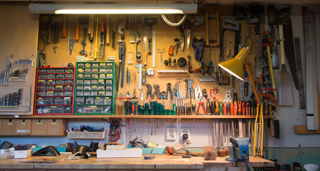 Complete workbench with a wall of tools in a workshop. - obrazy, fototapety, plakaty