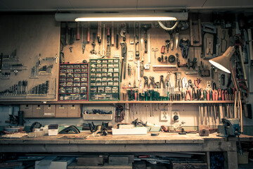 Complete workbench with a wall of tools in a workshop. Vintage look. - obrazy, fototapety, plakaty