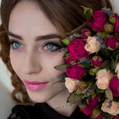 Girl with blue eyes and a bouquet of red roses. Portrait of a girl.
