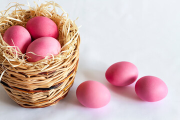 Naklejka na ściany i meble Easter composition with wicker basket and pink colored eggs