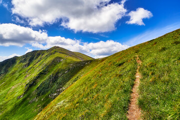 Mountain path hiking or trekking landscape, summer nature outdoor road view. Adventure tourism scenic way trail. Blue sky and clouds, sunny beautiful day.