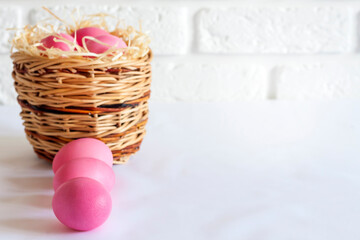 Easter composition with wicker basket and pink colored eggs