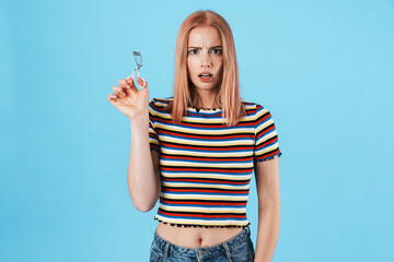 Image of beautiful shocked woman posing with eyelashes curler