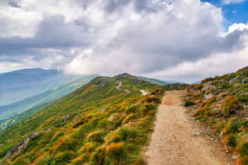 Mountain path hiking or trekking moody landscape Carpathian valley, summer nature outdoor road. Adventure tourism scenic way trail. Blue sky and clouds, sunny beautiful day.
