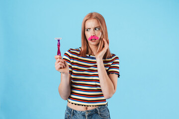 Image of beautiful shocked woman with fake mustache holding razor